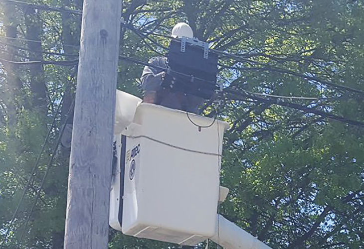 service tech in bucket truck up near power lines working on splicing cable